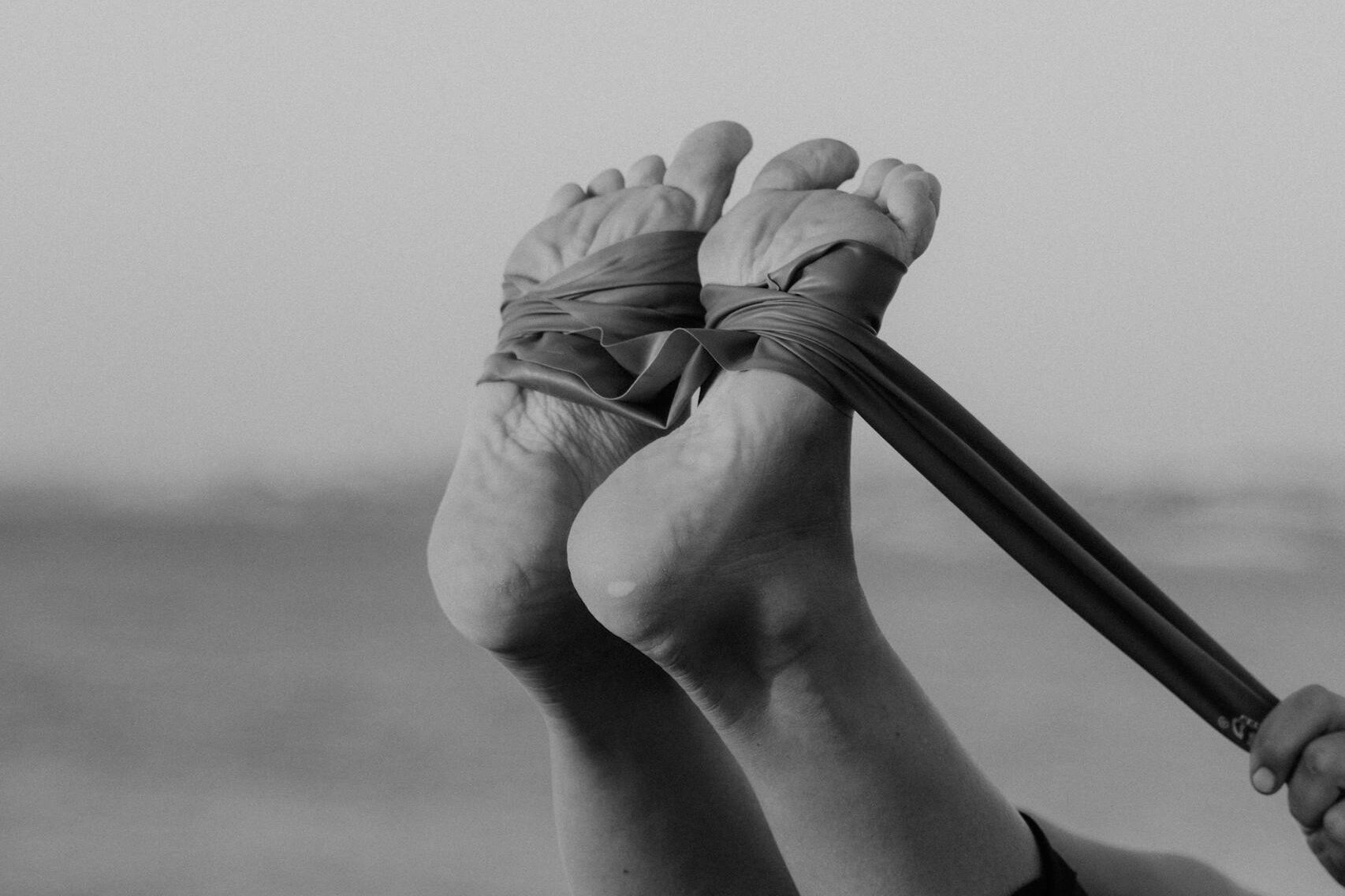 Black and white image of a stretching exercise using a resistance band.