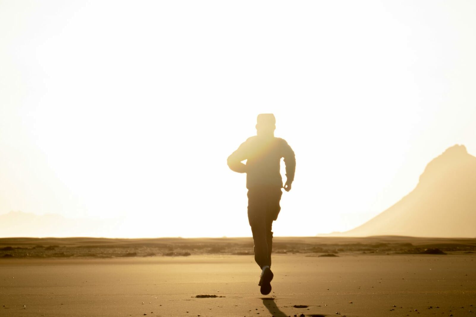 Silhouette of an adult running on the beach during sunrise, capturing the essence of solitude and adventure.